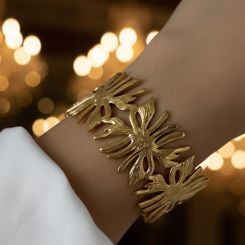 Gold leaf bracelet on a wrist with a white fabric background