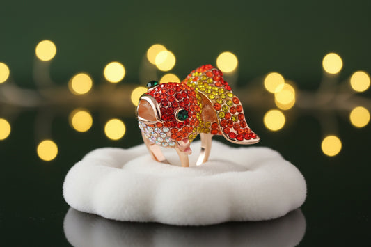 Colorful fish-shaped ring with gemstones on a white background