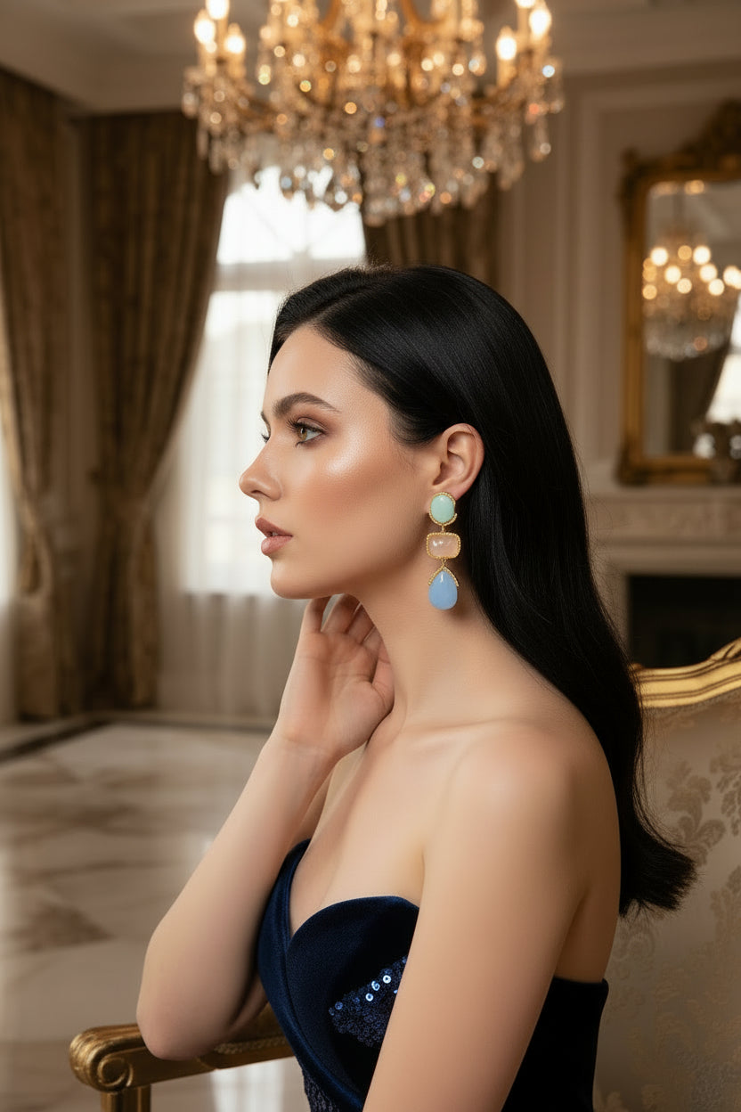 Pair of earrings with gold accents and multicolored stones on a white background