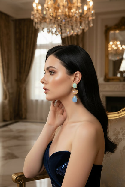 Pair of earrings with gold accents and multicolored stones on a white background