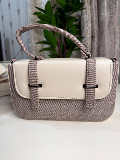 Handbag with beige top section and brown textured bottom on a white surface.