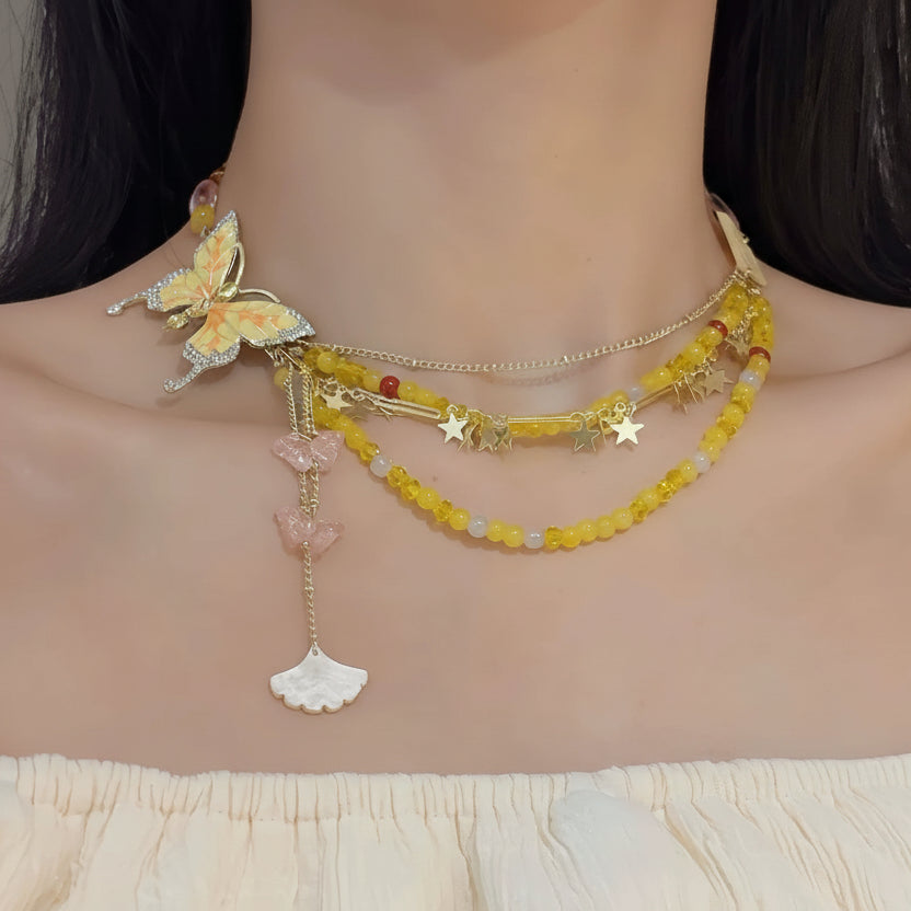 Necklace with butterfly and shell design worn by a model on a neutral background