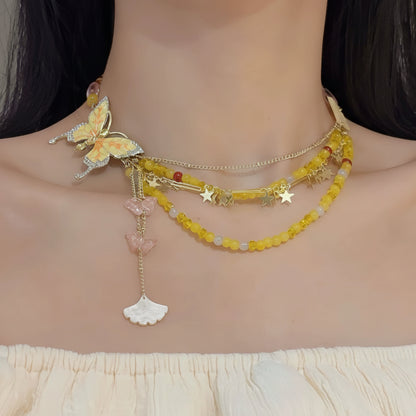 Necklace with butterfly and shell design worn by a model on a neutral background