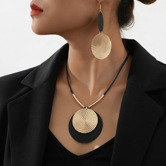 Close-up of a person wearing gold and black circular earrings and necklace.