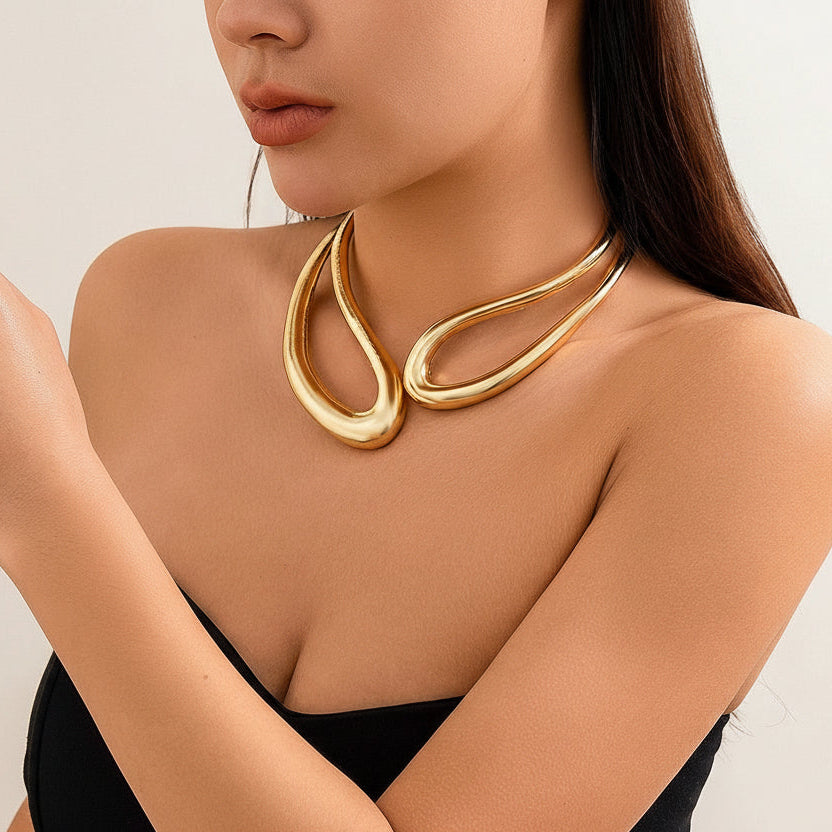 Woman wearing a gold necklace and bracelet on a neutral background