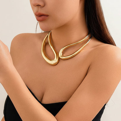 Woman wearing a gold necklace and bracelet on a neutral background