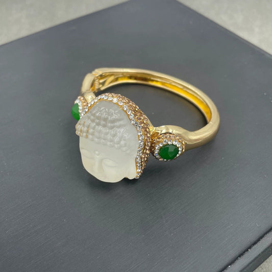 Gold ring with a white stone and green accents on a dark surface